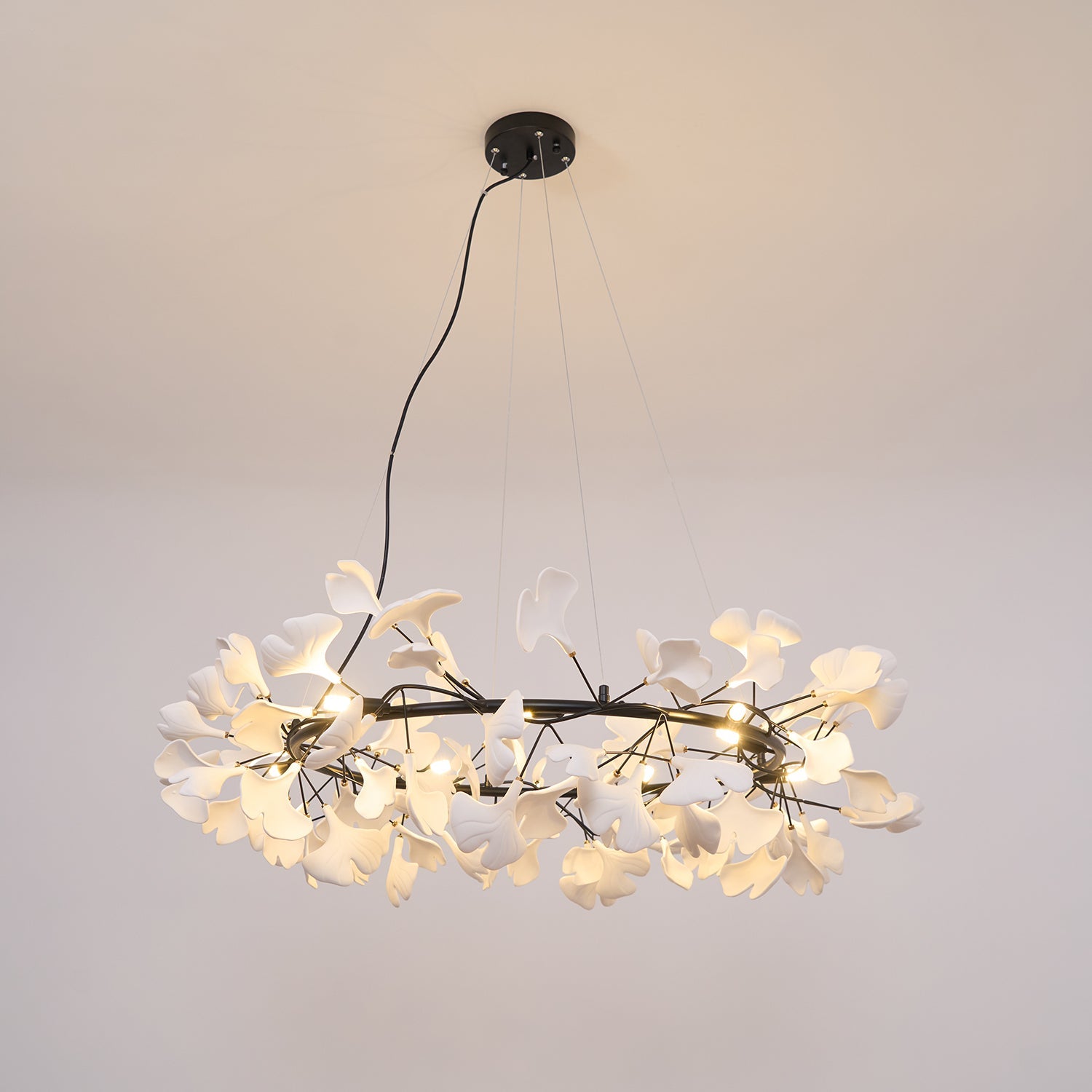 Porcelain ginkgo leaf chandelier glowing above a styled room