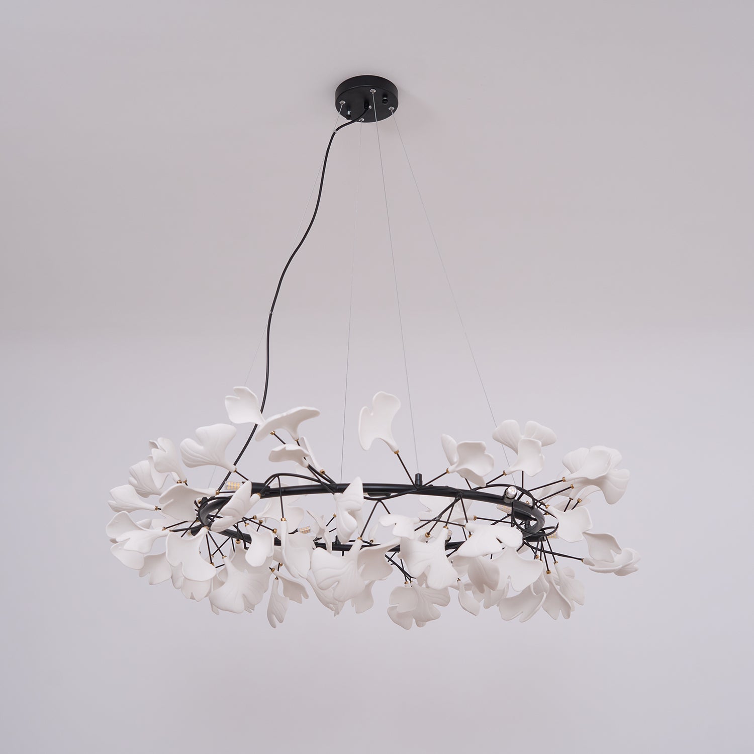 White porcelain ginkgo chandelier lit warmly over a table