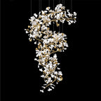 Closer view against black of the chandelier's spiral, showing how densely the porcelain leaves cluster on the gold stems.