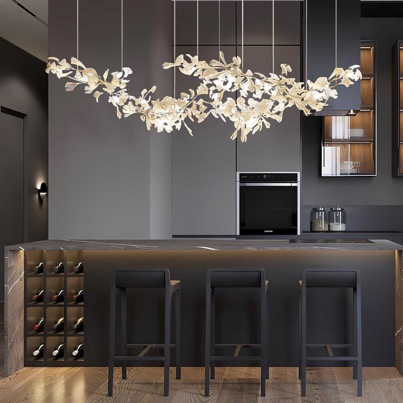 The chandelier lit above a dark kitchen island with bar stools and a built-in wine rack.