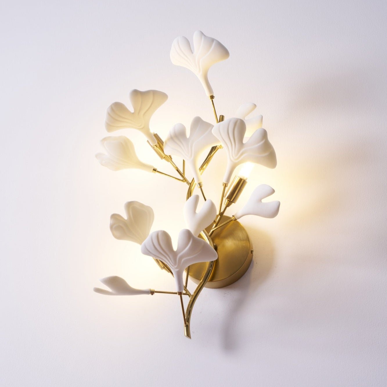 Ceramic ginkgo leaf wall lamp glowing warm on a wall