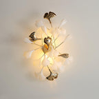 Gold ginkgo leaf wall lamp glowing softly on a wall