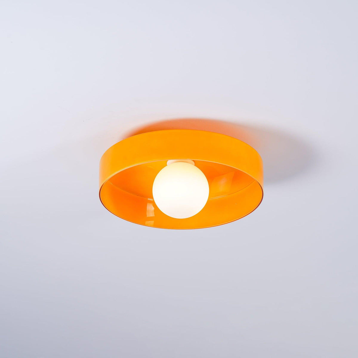 A smaller, distant view of this Clérachic orange ceiling light against a plain grey backdrop.