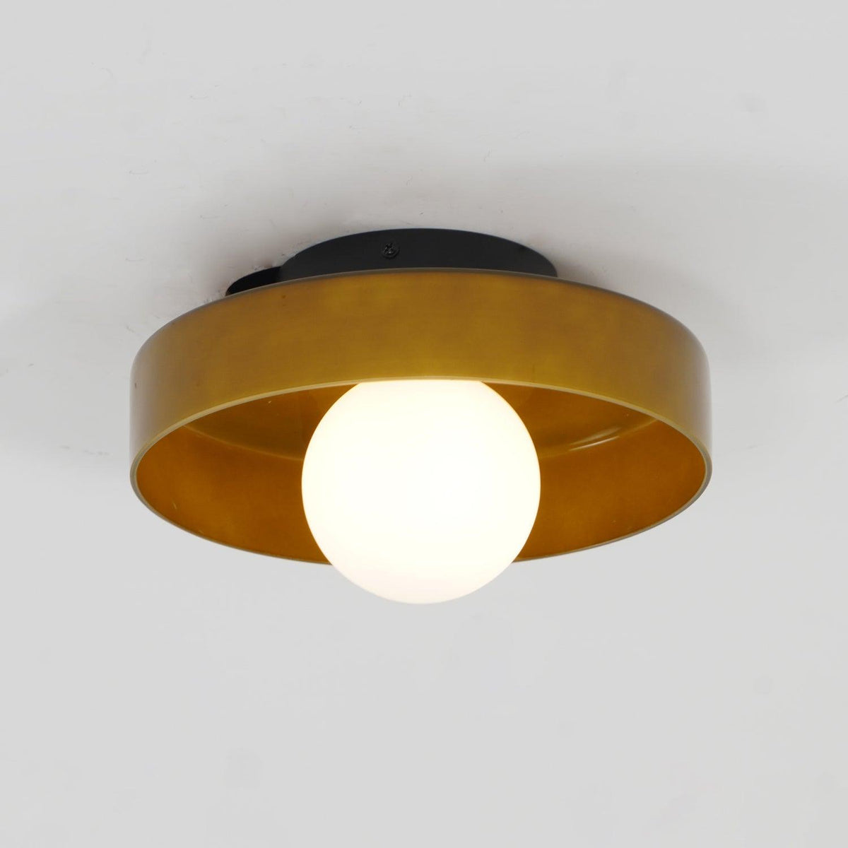 Lit against a plain grey backdrop, this Clérachic ceiling light in warm brown glass glows softly from within.