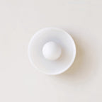 This Clérachic ceiling light in white glass seen from below, its ball unlit against a pale wall.