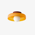 This Clérachic orange ceiling light with a maroon mounting plate, its white ball unlit against a plain wall.
