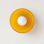 An orange disc-shaped wall light photographed straight on, a different mount from this Clérachic ceiling light.