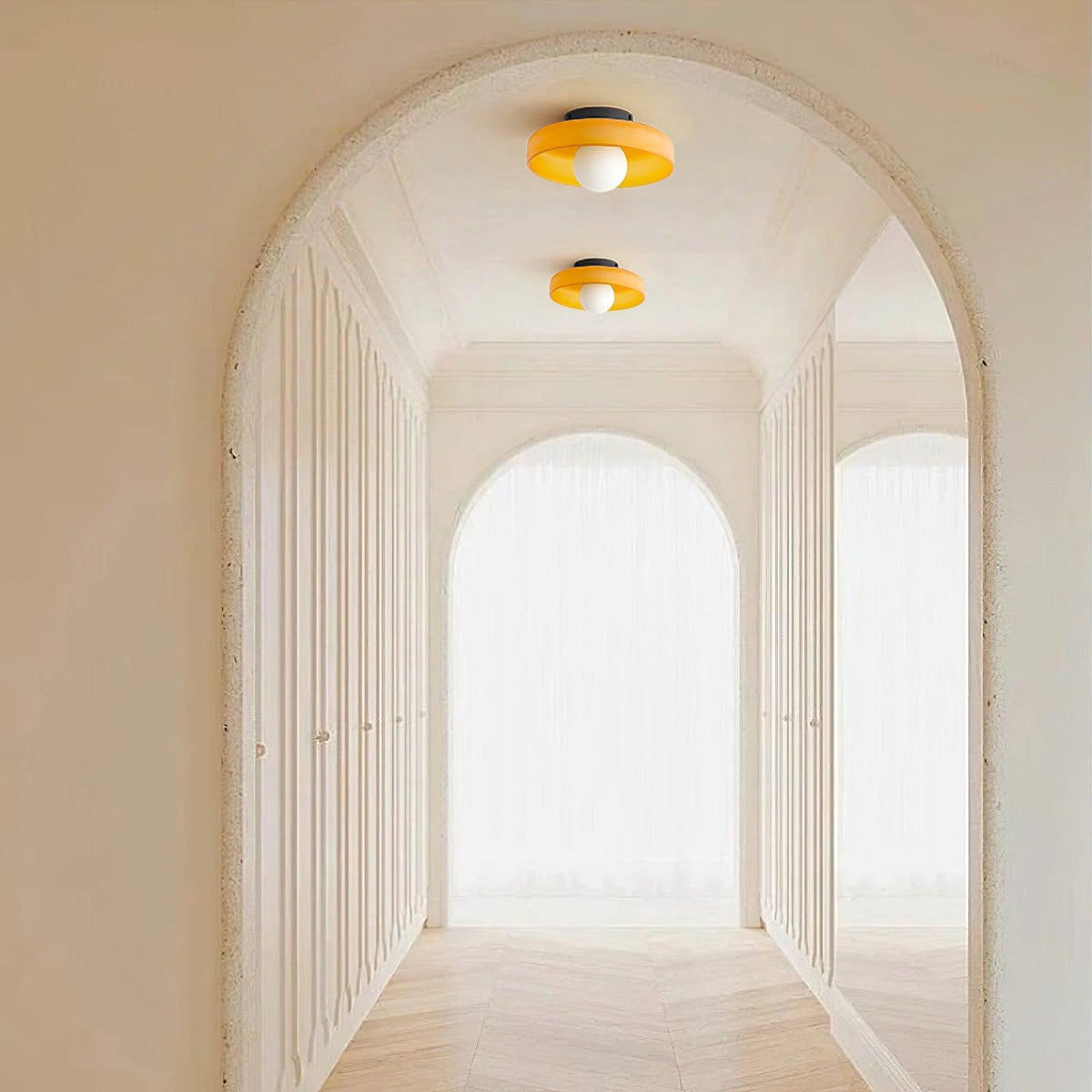 A hallway with a plastered archway, two of these Clérachic ceiling lights mounted in a row overhead.