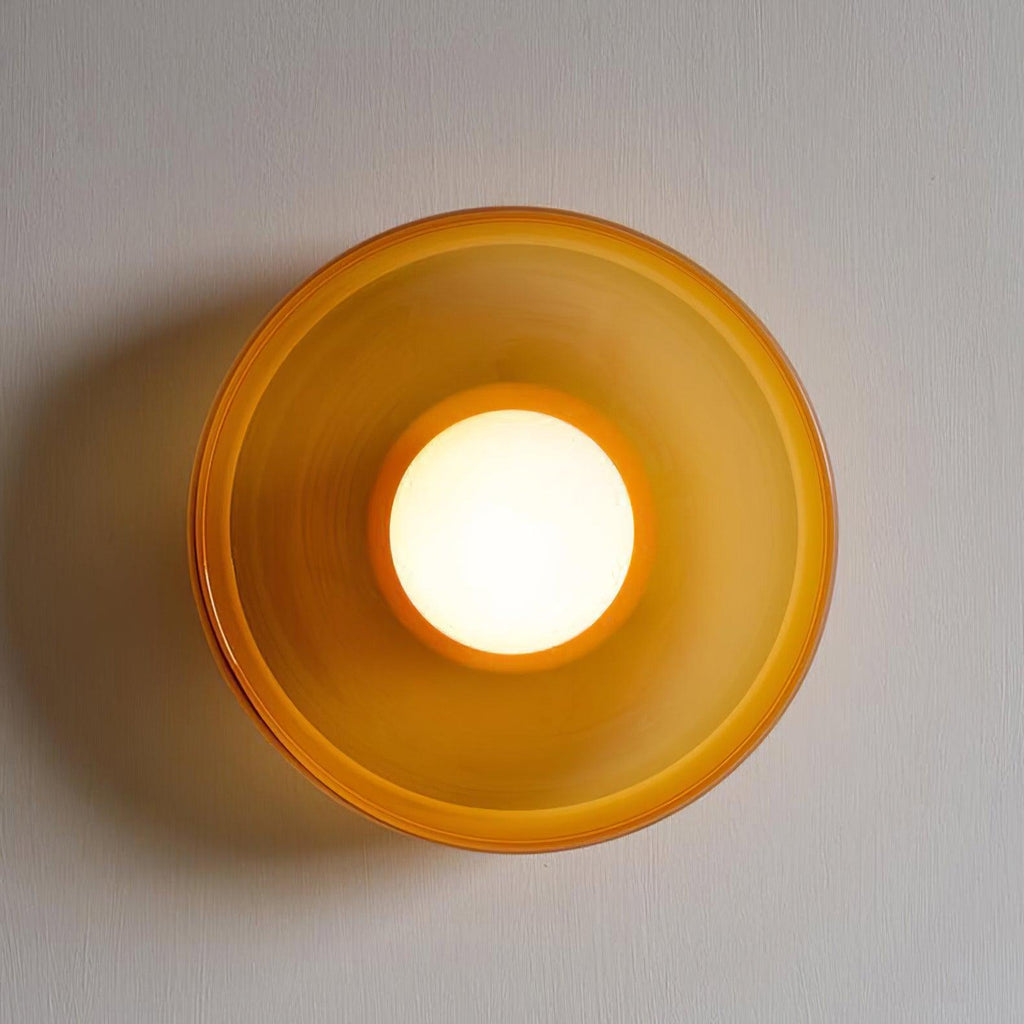 A large brown-toned wall light with its ball lit, mounted on a textured wall, a different fixture from this Clérachic ceiling light.