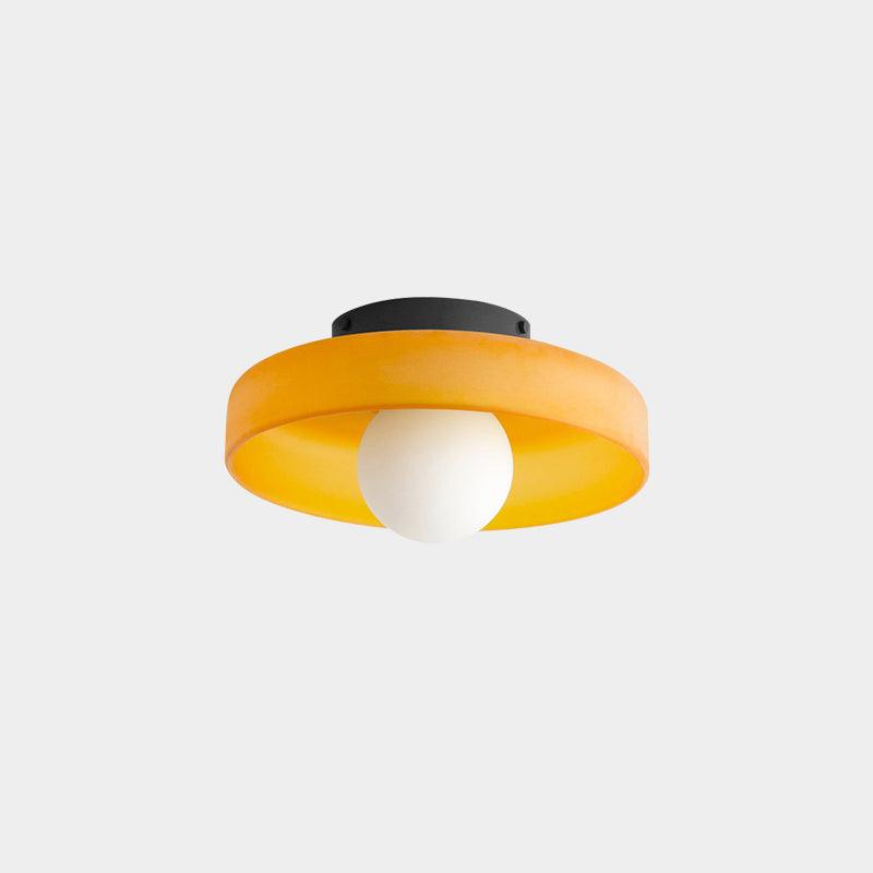 This Clérachic orange ceiling light with its dark mounting plate visible, ball unlit against a pale backdrop.