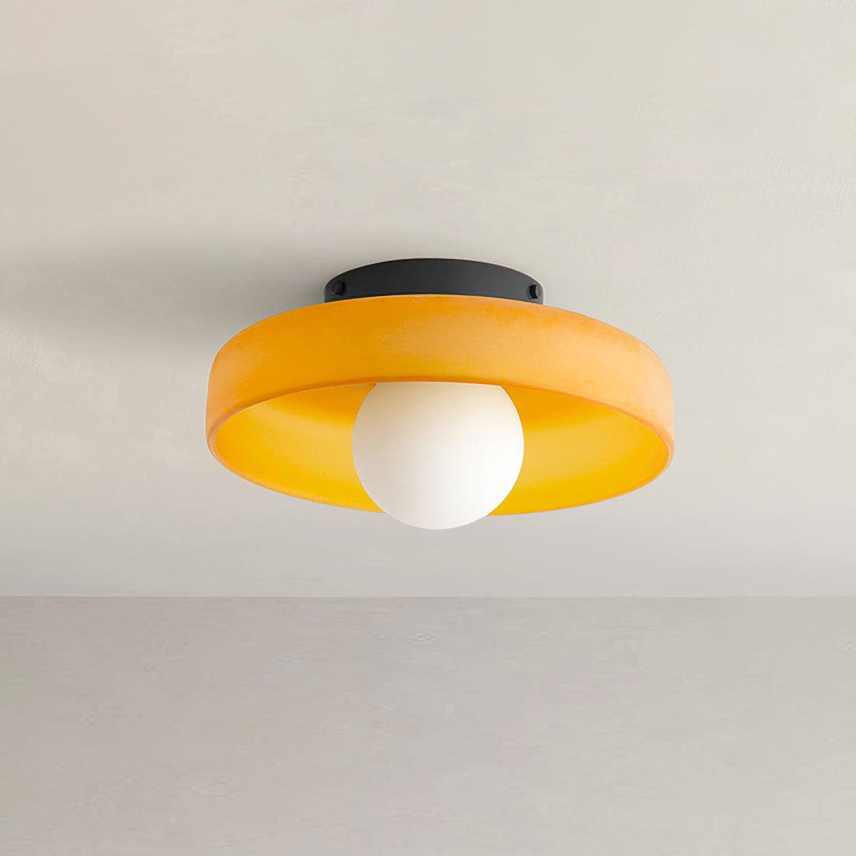 A Clérachic ceiling light in orange glass, mounted flush in a corner where the wall meets a plain ceiling.