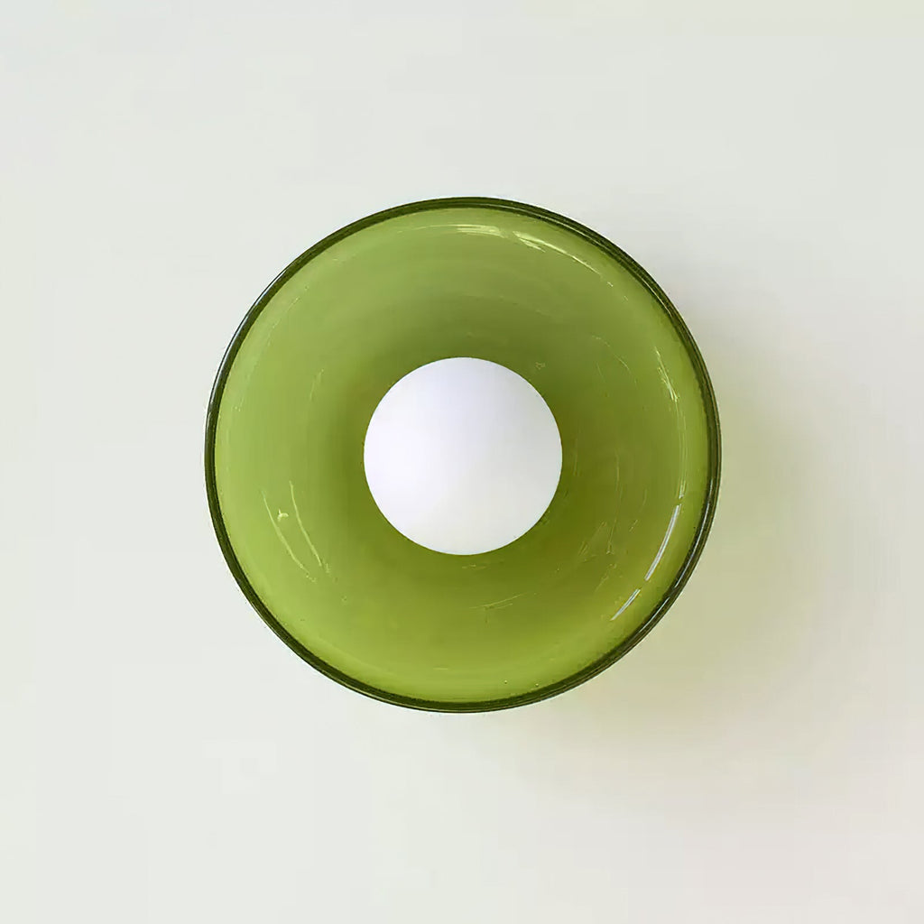 A green disc-shaped wall light with its ball centred in the ring, a different fixture from this Clérachic ceiling light.