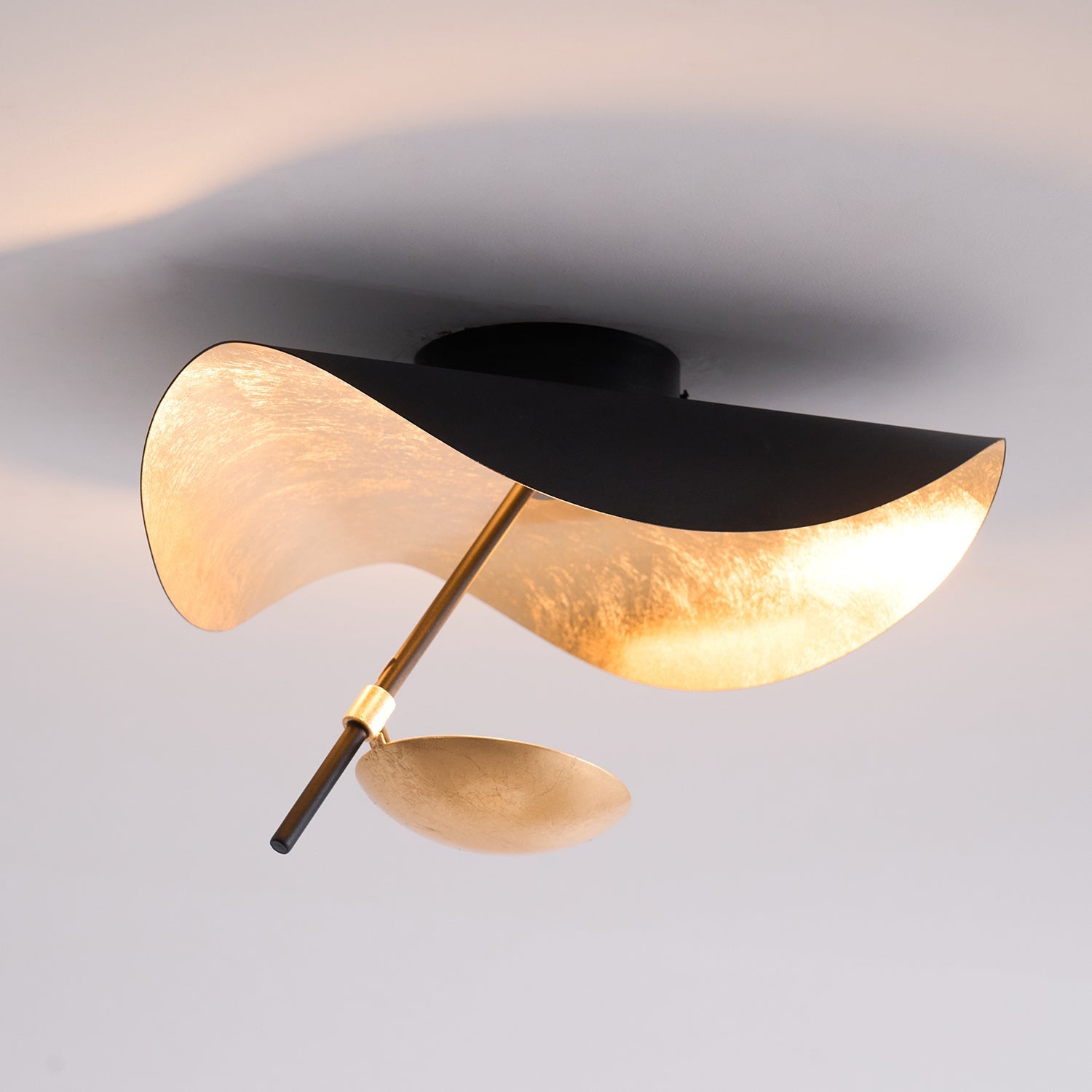 Curved steel disc ceiling light above a seating area