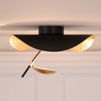 Curved steel disc light glowing against a plain ceiling