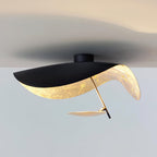 Curved steel disc ceiling light in a minimal room