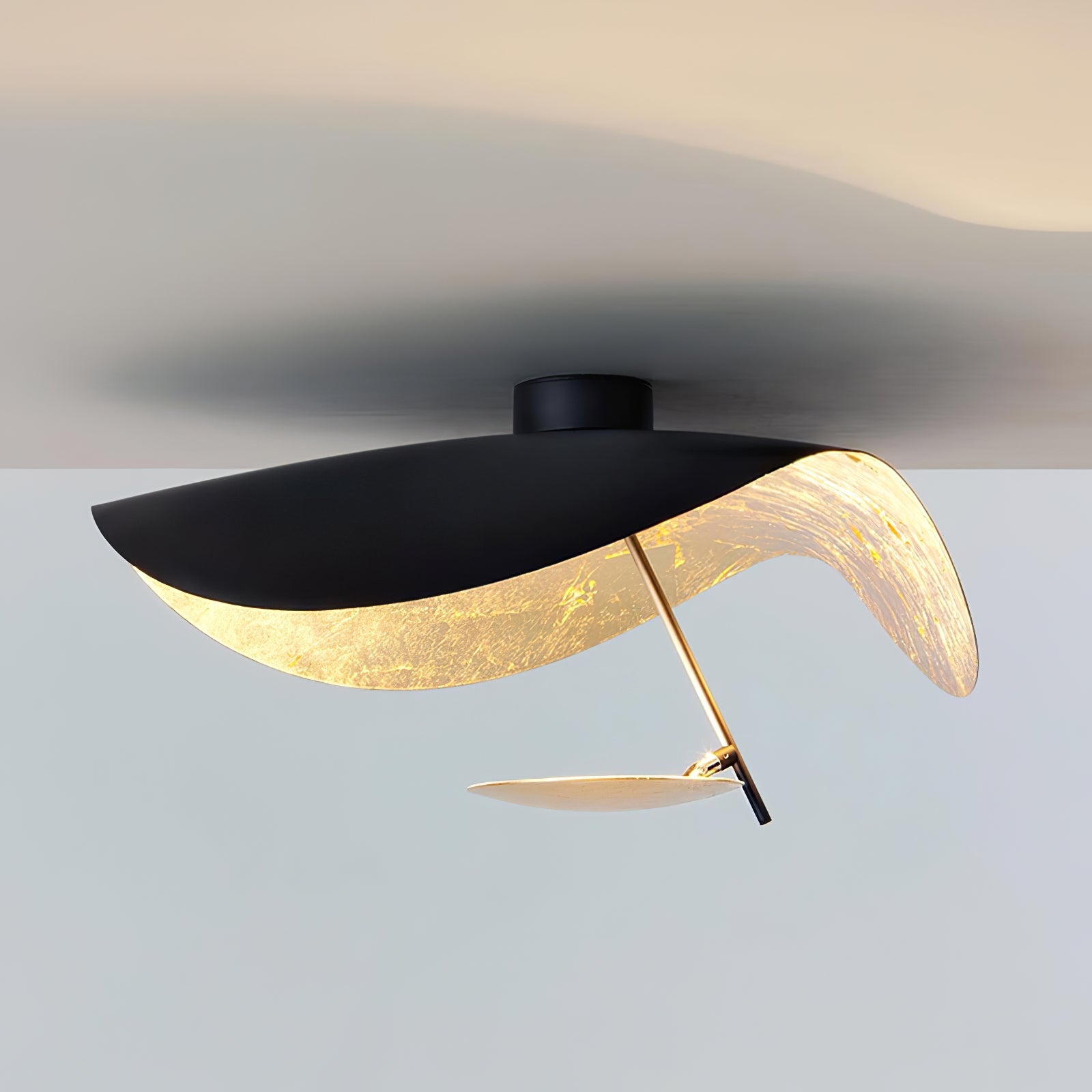 Curved steel disc ceiling light in a minimal room