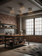 Viewed from below, several black Clérachic spotlights line a brick kitchen ceiling above a wooden table.