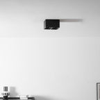 From a wider angle in the office, a black two-light Clérachic spotlight is mounted near the ceiling corner, unlit.