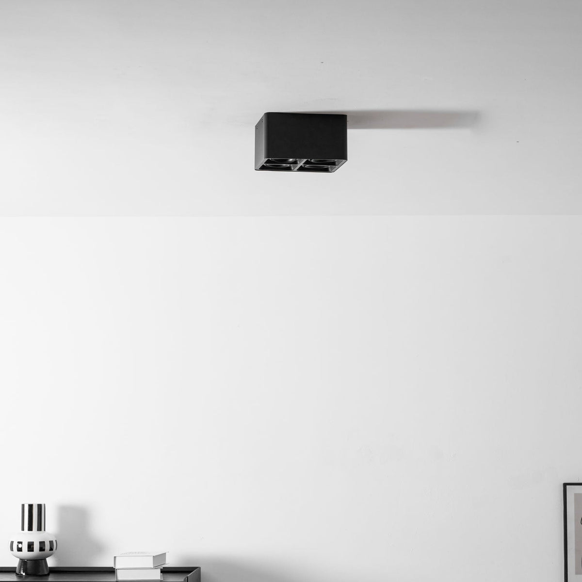 From a wider angle in the office, a black two-light Clérachic spotlight is mounted near the ceiling corner, unlit.