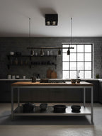 Near a kitchen window with dark cabinetry, a small black Clérachic spotlight sits mounted on the ceiling.