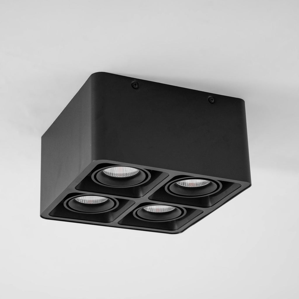 Angled from below, this black four-light Clérachic spotlight sits unlit against a plain white background.