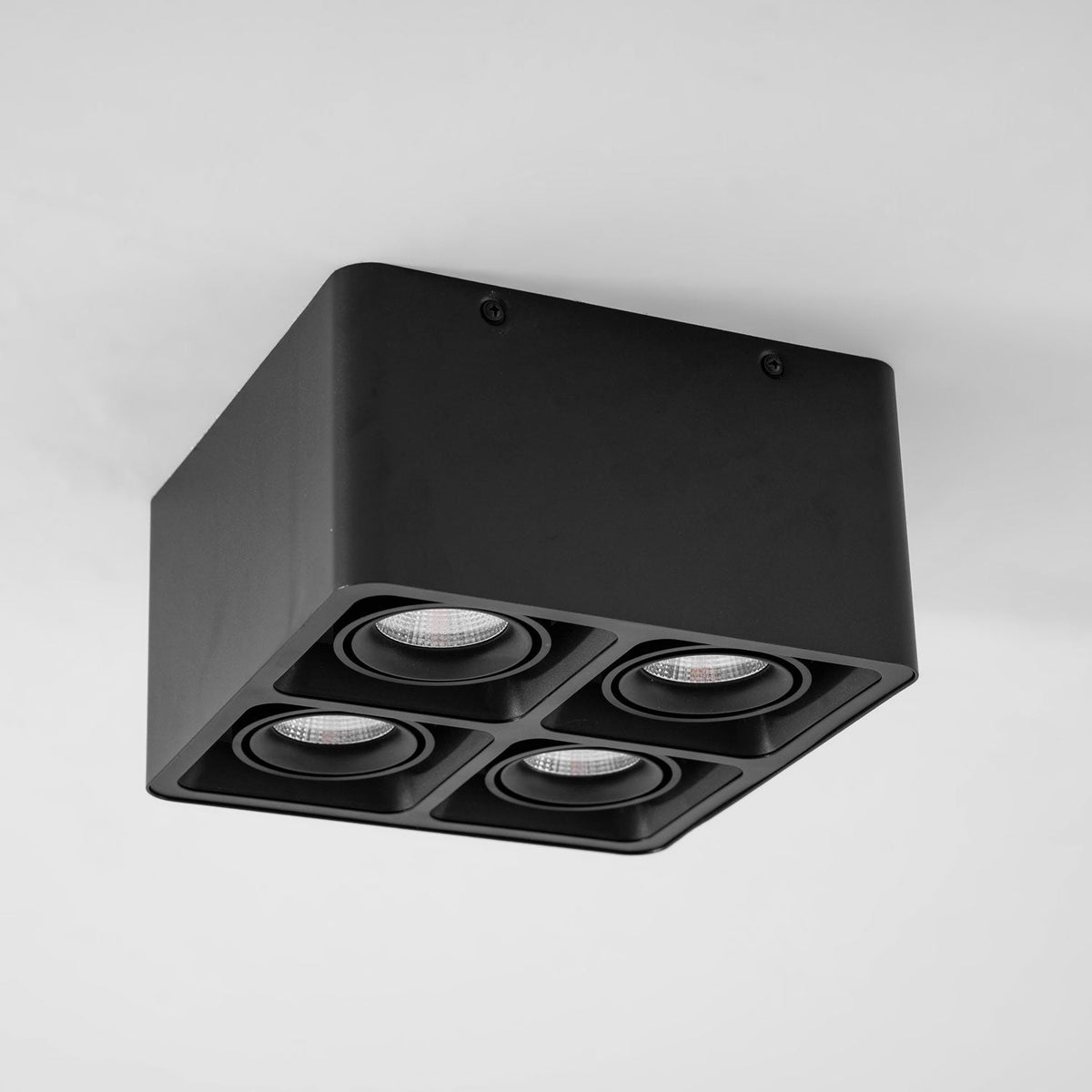 Angled from below, this black four-light Clérachic spotlight sits unlit against a plain white background.