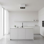 In a bright white kitchen, a white two-light Clérachic spotlight glows warm from the ceiling.