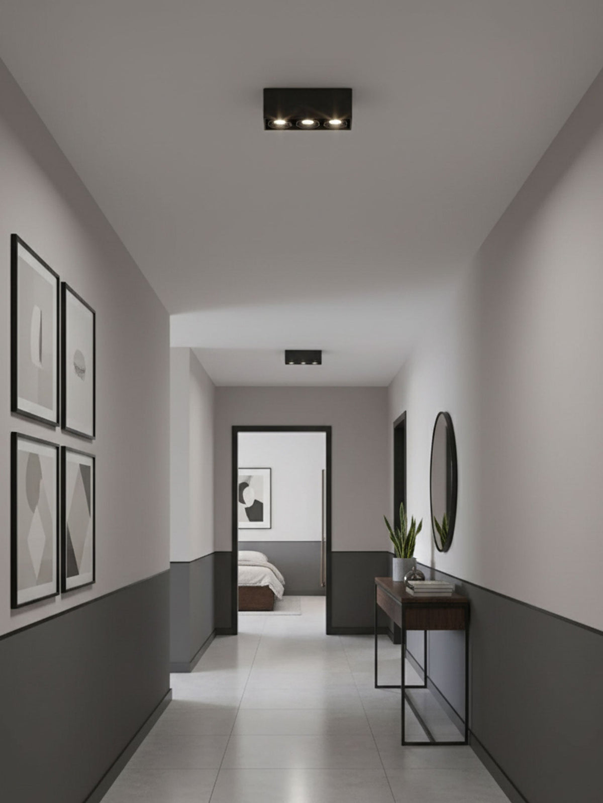 In a hallway lined with framed pictures, a black two-light Clérachic spotlight sits unlit on the ceiling.
