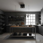 Mounted above an industrial kitchen with brick walls and open shelving, a single black Clérachic spotlight sits on the ceiling.