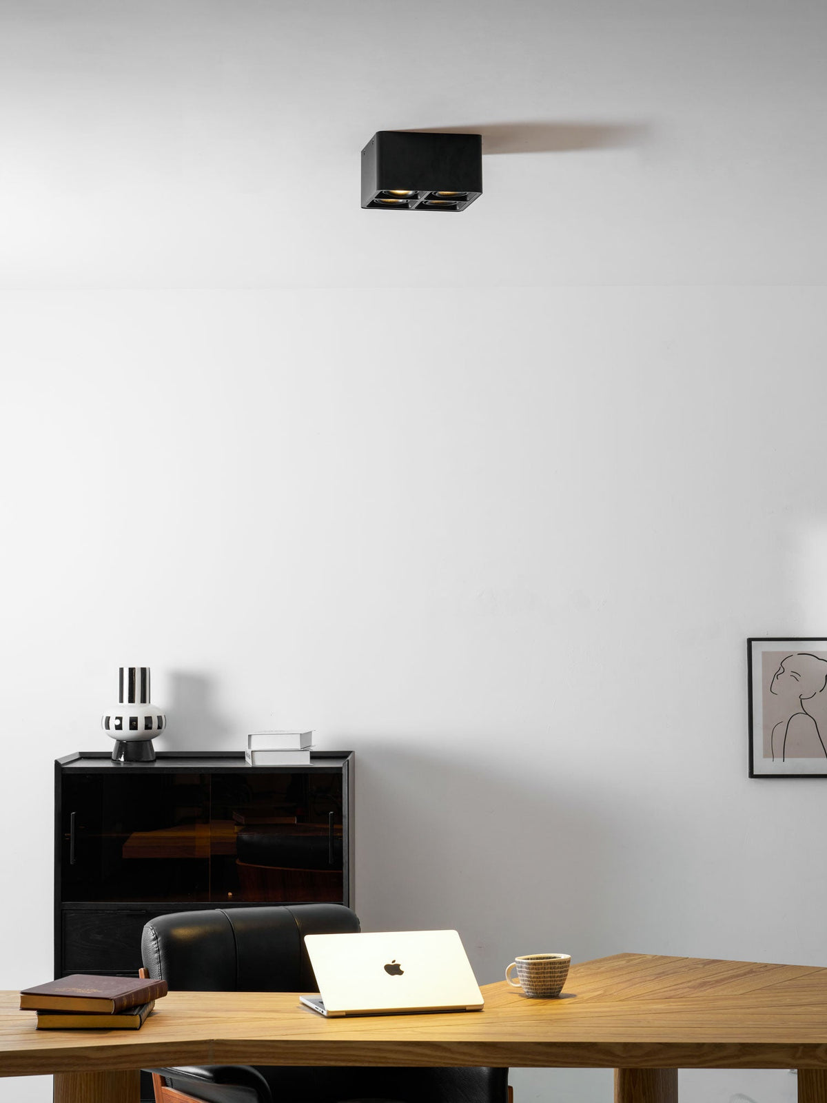 In a home office with a wooden desk and laptop, a single black spotlight sits high on the ceiling from Clérachic.