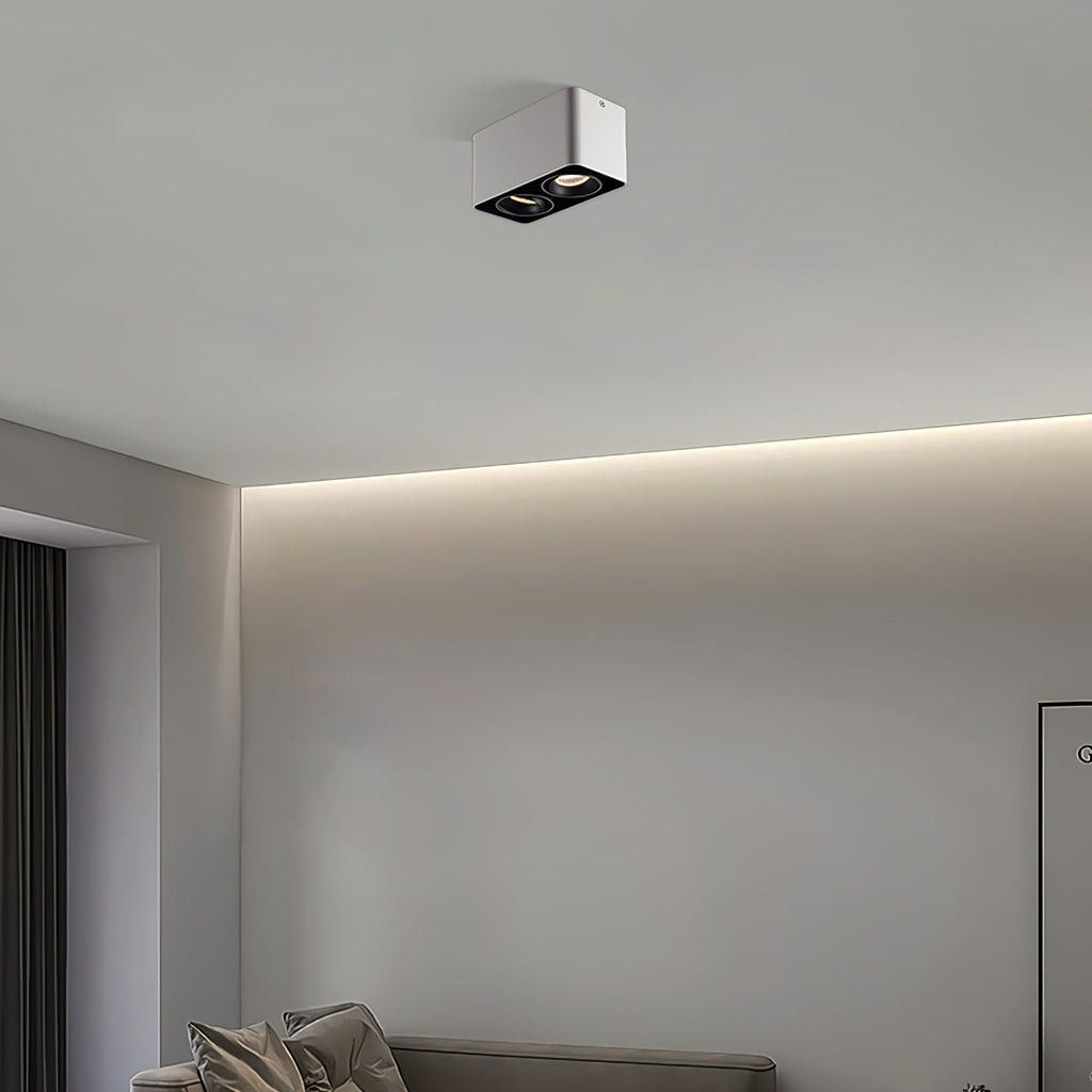 Above a bed beside an indirect light strip, a white two-light Clérachic spotlight sits unlit on the ceiling.
