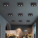Inside a flower shop, a row of black single-light Clérachic spotlights glows warm above shelves of blooms.