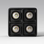 Seen front-on in a product render, this black four-light Clérachic spotlight glows warm on a plain background.