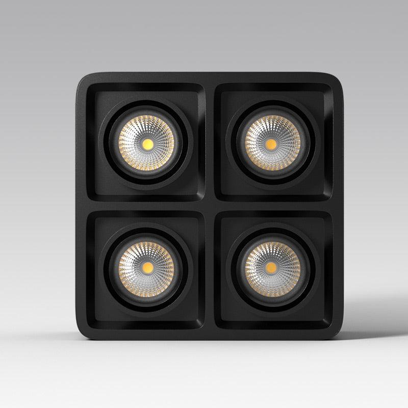 Seen front-on in a product render, this black four-light Clérachic spotlight glows warm on a plain background.
