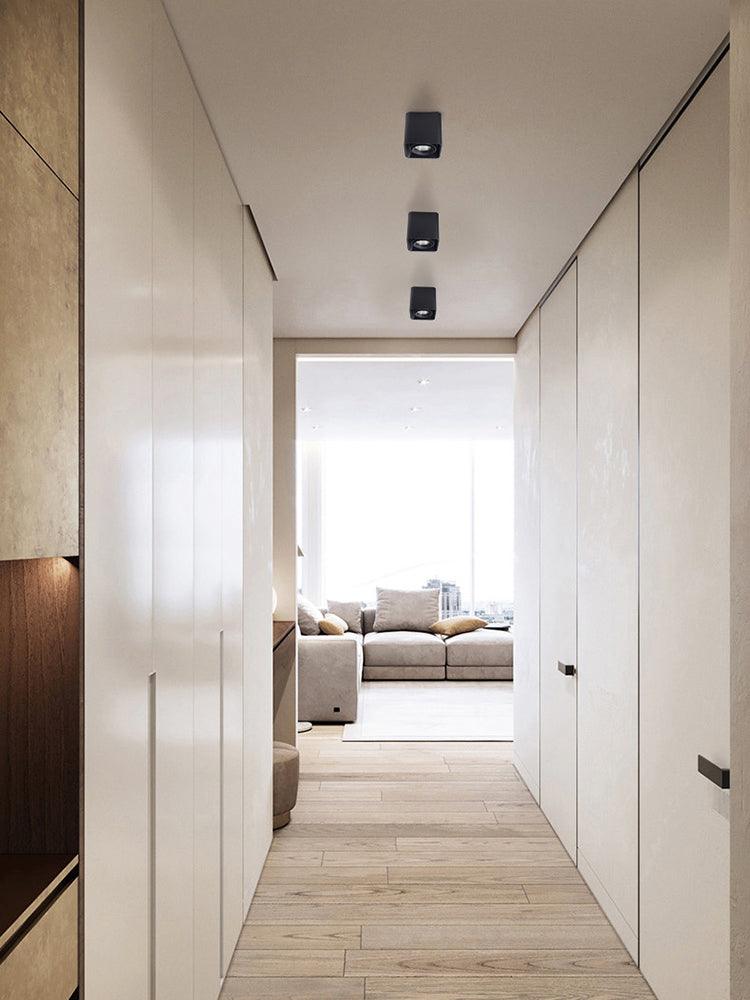 Along a wood-panelled hallway, three black single-light Clérachic spotlights sit unlit in a row on the ceiling.