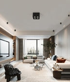 Above a sculptural chair and floor-to-ceiling window, a black two-light Clérachic spotlight sits unlit on the ceiling.
