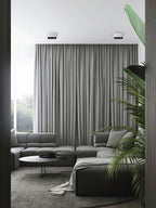 Viewed through a doorway, two white single-light Clérachic spotlights sit unlit above a sectional sofa.