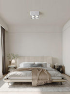 Above a neatly made bed, a white two-light Clérachic spotlight sits unlit on the ceiling.