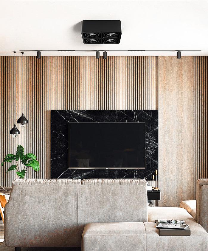 Against a wood-slat wall near a television, a black two-light Clérachic spotlight sits unlit on the ceiling.