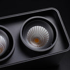 Close view of two lamp heads on this black Clérachic spotlight, one glowing warm, the other soft-focus behind it.