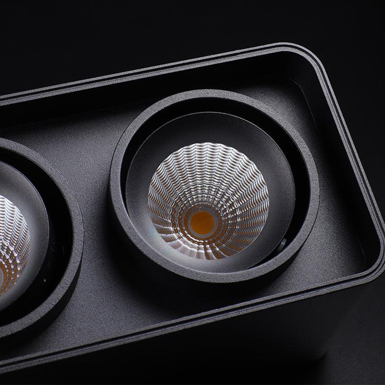 Close view of two lamp heads on this black Clérachic spotlight, one glowing warm, the other soft-focus behind it.
