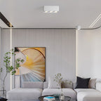 Above a gallery wall of framed art, a white three-light Clérachic spotlight sits unlit on the ceiling.