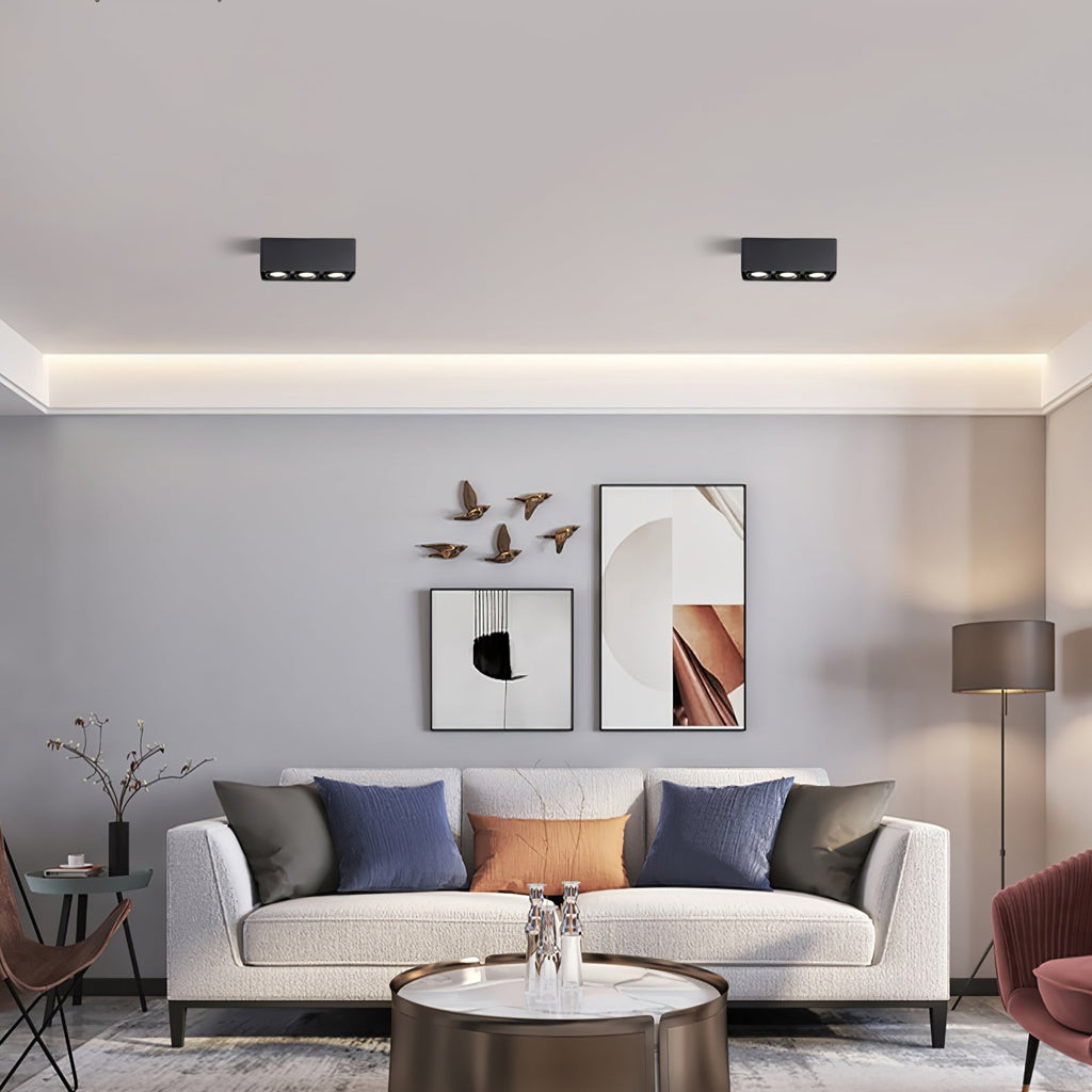 Above a gallery wall and colourful cushions, two black two-light Clérachic spotlights sit unlit on the ceiling.