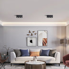 Above a gallery wall and colourful cushions, two black two-light Clérachic spotlights sit unlit on the ceiling.