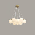 Lit warmly on a grey backdrop, this Clérachic cluster chandelier's frosted globes glow beneath a gold ceiling plate.