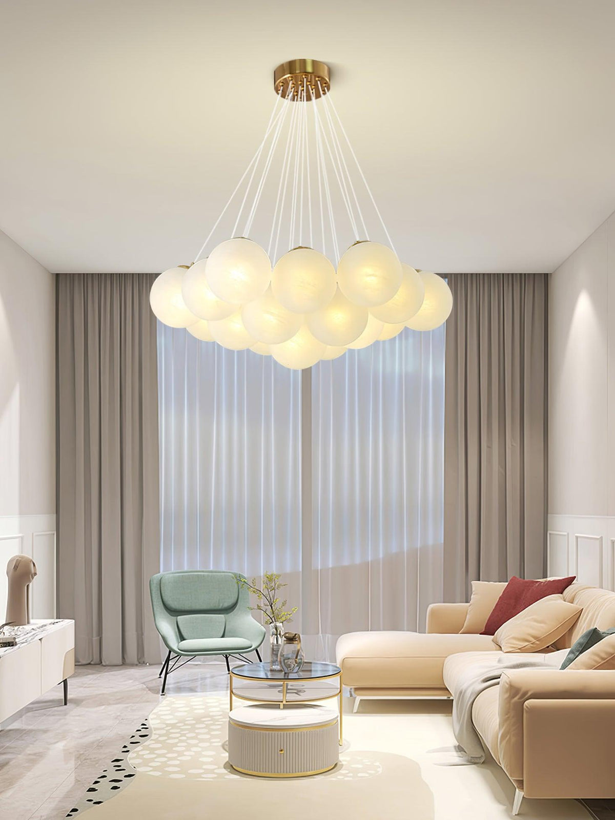 A green armchair and pale sofa sit beneath this lit Clérachic cluster chandelier in a neutral living room.