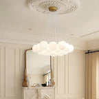 This Clérachic cluster chandelier hangs above a marble mantel and gilt mirror, its frosted globes softly lit.