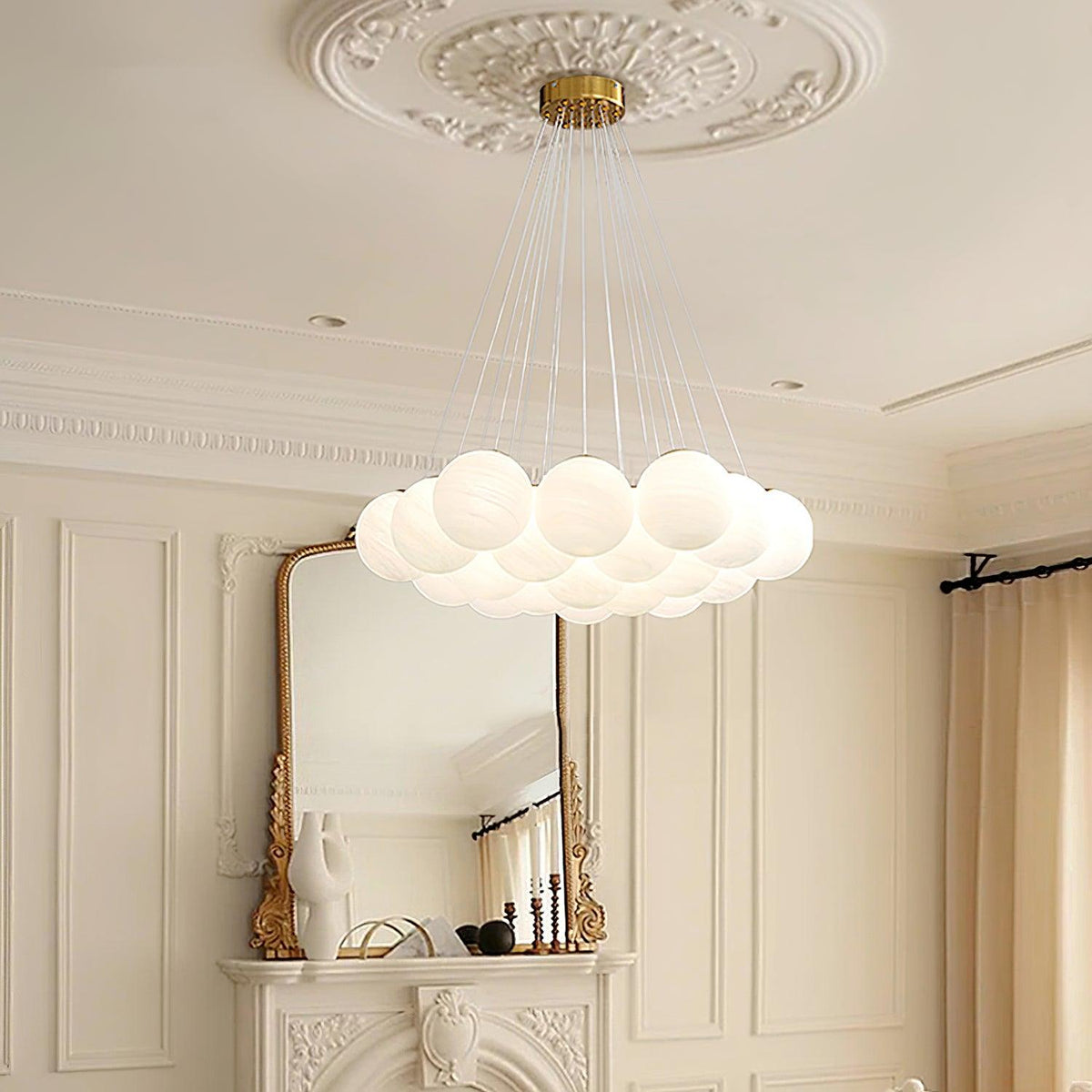 This Clérachic cluster chandelier hangs above a marble mantel and gilt mirror, its frosted globes softly lit.