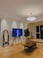 A floor mirror and television sit near this lit Clérachic cluster chandelier above a herringbone floor.