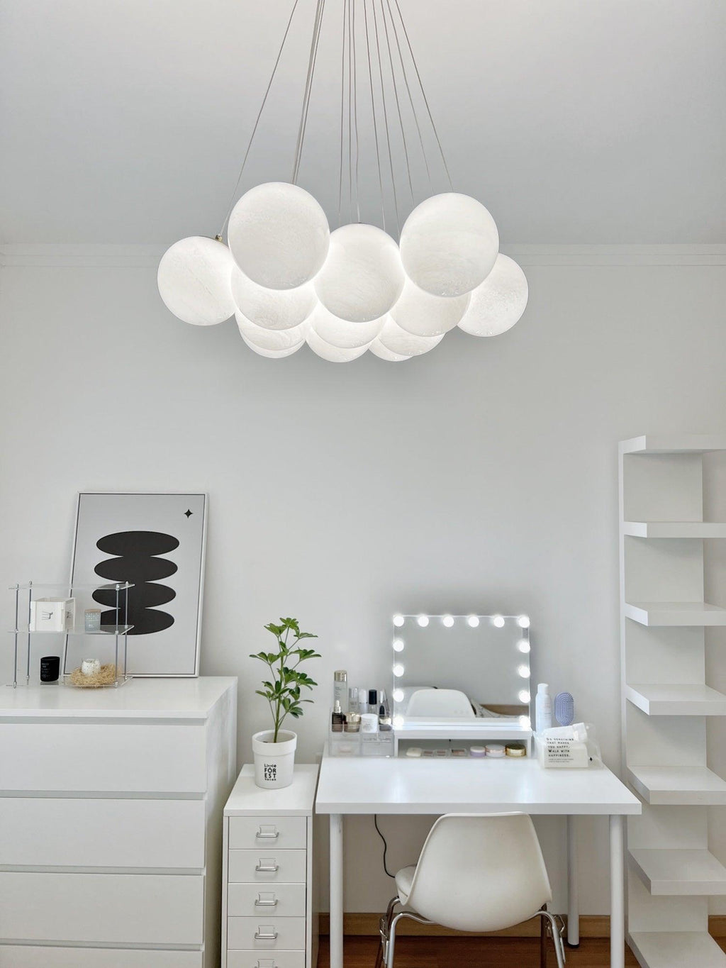Above a white dressing table and mirror, this Clérachic cluster chandelier glows in a small study nook.